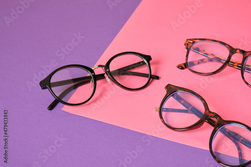 different eyeglasses on pink and purple geometric background, trendy eyeglass frames copy space