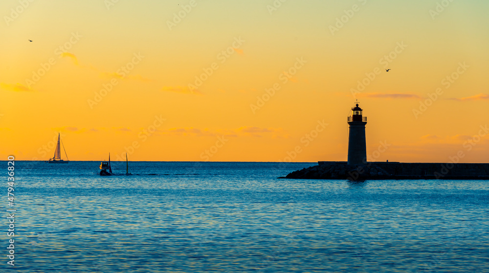 sunset over the sea with a clear sky and a lighthouse in the foreground 