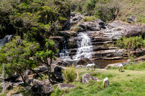Famous Frades waterfall with bathing pond and white horses in pasture, Vale do Frade, Teresopolis, Rio de Janeiro, Brazil photo