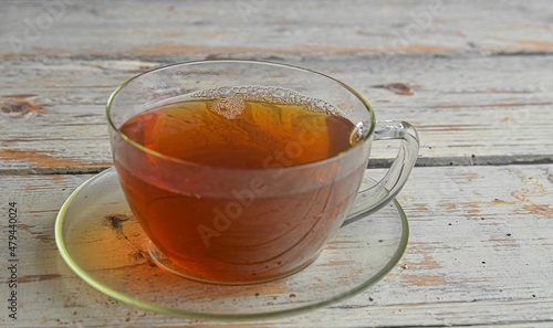 Delicious black tea in a transparent cup. Cup of tea on wooden rustic background