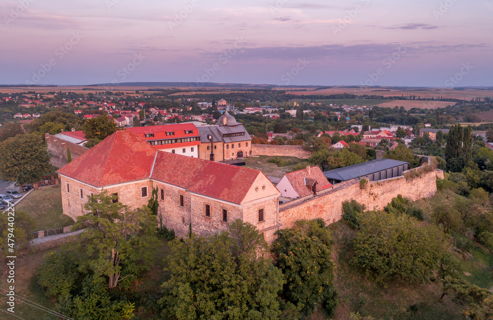 Aerial sunset shot of Pecsvarad fortified church, abbey  and castle with tower, gate on a hilltop in Baranya county Hungary with dramatic colorful sky