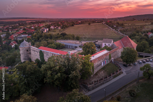 Aerial view of the fortified church and monastery of Pecsvarad in Baranya county with towers, walls and medieval buildings on a hilltop above the village in Hungary dramatic colorful sunset sky photo