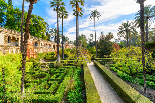 The landscaped gardens of palm trees and manicured grounds inside the Royal Alcázar of Seville Spain.