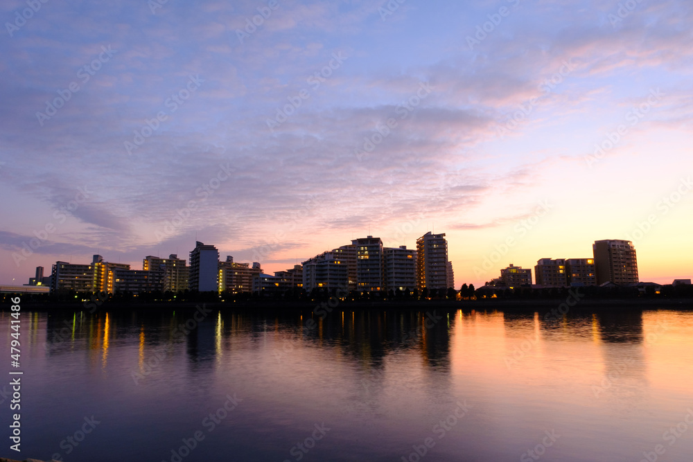 夜明け前の都市景観。太陽が昇前のマジックアワー。あたりがオレンジ色に染まる。兵庫県芦屋浜より西宮浜を臨む