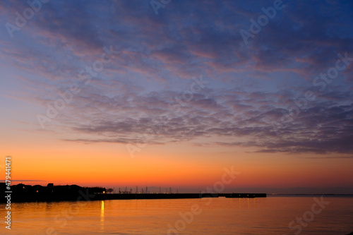 早朝、朝日にキラキラ輝き、黄金色に輝く海。兵庫県芦屋市芦屋浜より大阪湾を臨む。遠くに大阪南港のビルが見える © 宮岸孝守