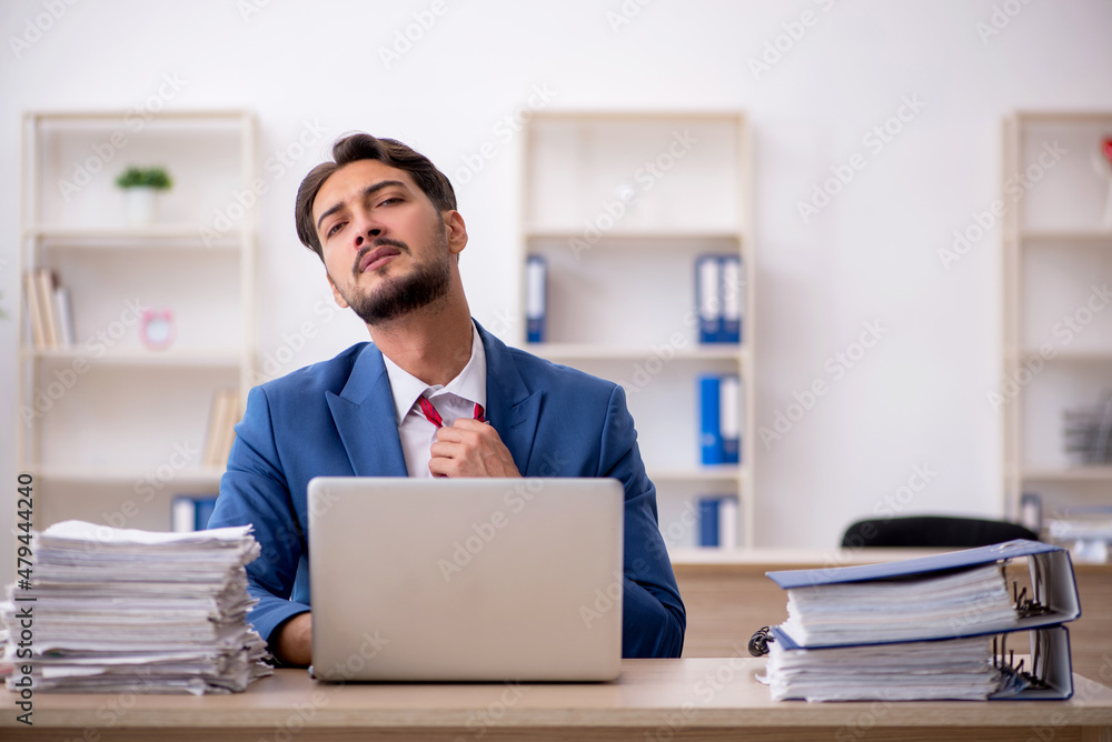 Young male employee and too much work in the office Young male employee and too much work in the office