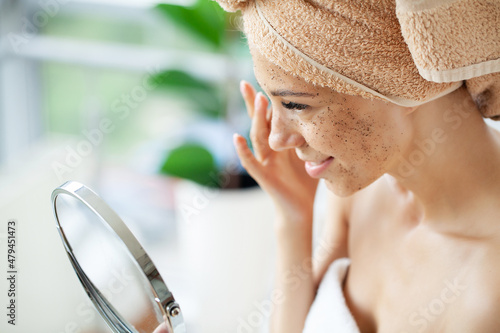 Close up of smiling woman applying coffee scrub on face