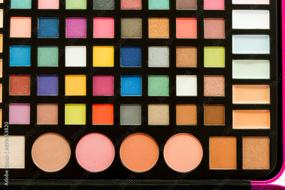 Close-up of a multicolored makeup palette, with shadows and blushes and compact foundation cream. Close-up of a multicolored makeup palette, with shadows and blushes and compact foundation cream.