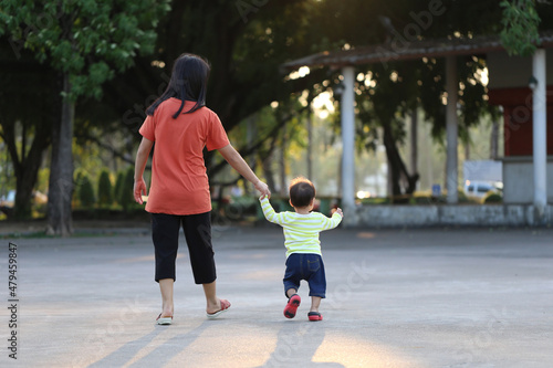 Mother and child holding a hand to walk in the park.