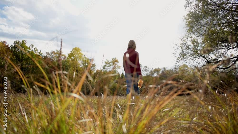 One girl is slowly walking along a field with autumn grass. People are one with nature. Health concept. Health care, authenticity, sense of balance and calmness. One girl is slowly walking along a field with autumn grass. People are one with nature. Health concept. Health care, authenticity, sense of balance and calmness.