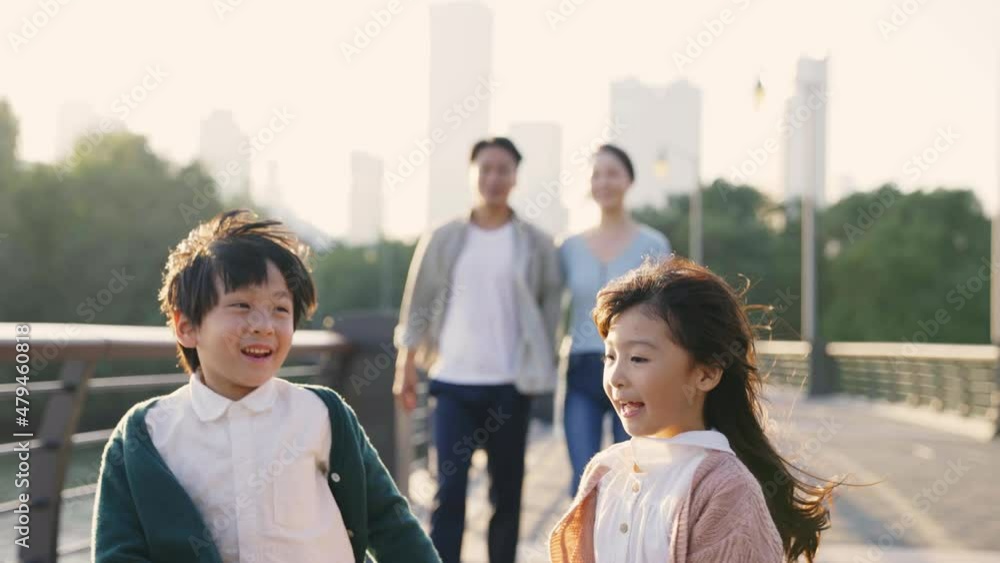 happy asian family with two children taking a walk in city park