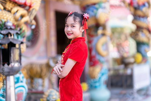 little Cute Asian girl wearing traditional Chinese cheongsam red with paper lanterns with the Chinese alphabet Blessings written on it Is a Fortune blessing compliment decoration for Chinese New Year © Thinapob