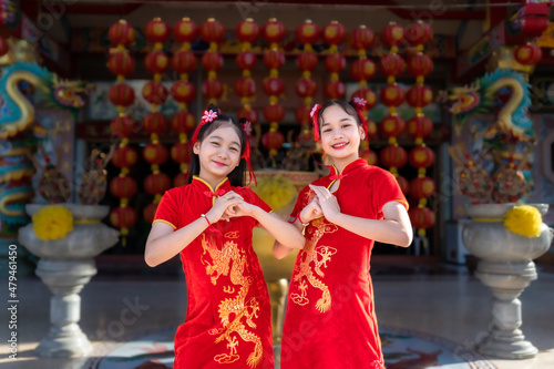 Portrait beautiful smiles Cute little Asian Two girl wearing red traditional Chinese cheongsam decoration for Chinese New Year Festival at Chinese shrine