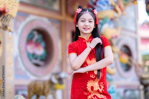 little Cute Asian girl wearing traditional Chinese cheongsam red with paper lanterns with the Chinese alphabet Blessings written on it Is a Fortune blessing compliment decoration for Chinese New Year