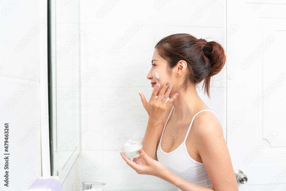 Asian Woman applying cosmetic cream reflection in the mirror. Asian Woman applying cosmetic cream reflection in the mirror.