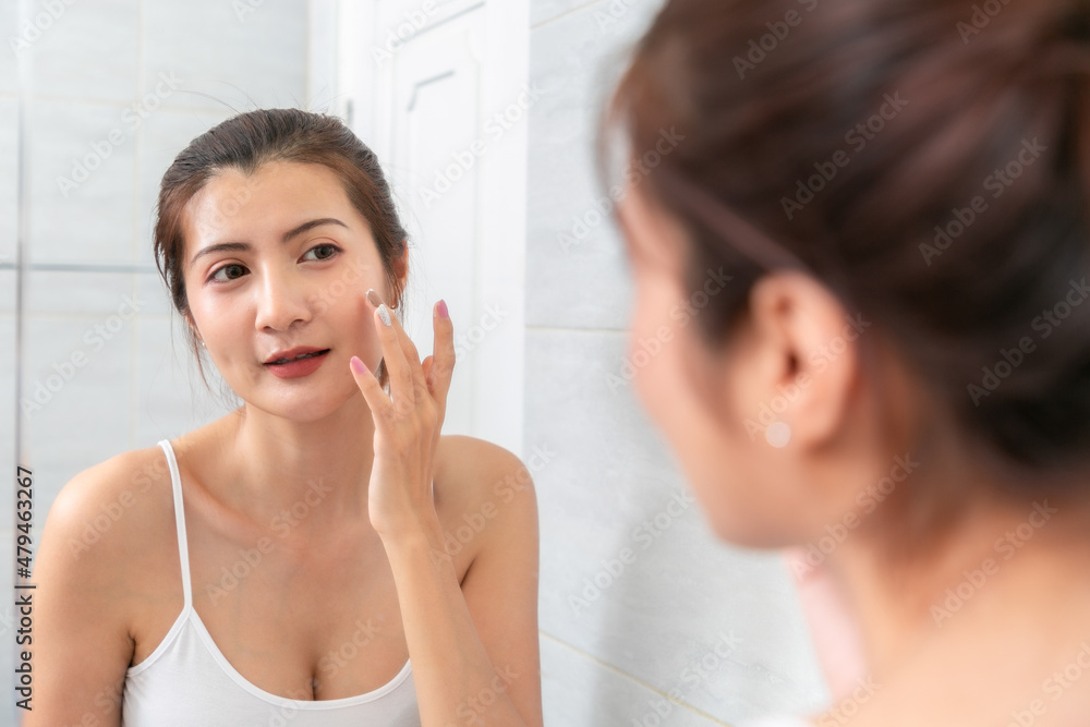 Asian Woman applying cosmetic cream reflection in the mirror. Asian Woman applying cosmetic cream reflection in the mirror.