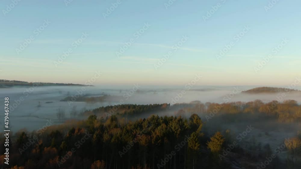 Drone rise reveal of blanket of low hanging fog sitting on fields in British countryside Drone rise reveal of blanket of low hanging fog sitting on fields in British countryside