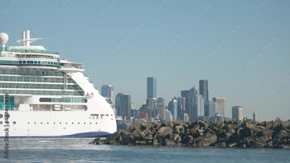 Low wide angle shot of the large boat at cruise ship terminals on the ocean water waves flowing to the rocks on a sunny day with high buildings at the background in Seattle, WA USA. 4K Low wide angle shot of the large boat at cruise ship terminals on the ocean water waves flowing to the rocks on a sunny day with high buildings at the background in Seattle, WA USA. 4K