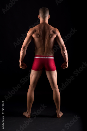 Studio photo of the back of strong man, black background