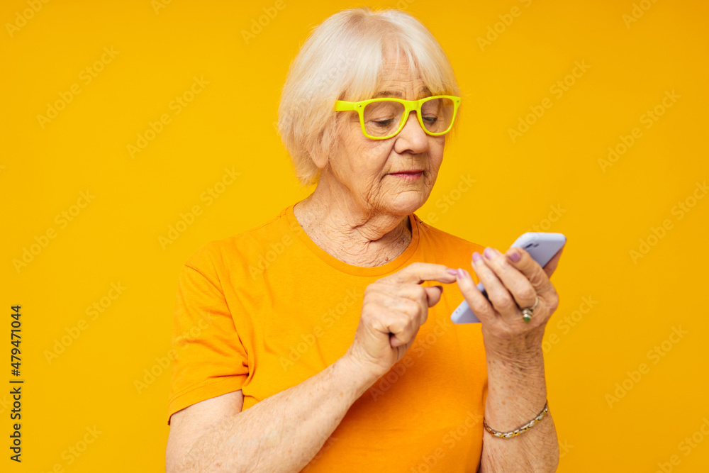 smiling elderly woman happy lifestyle in yellow t-shirts with phone yellow background smiling elderly woman happy lifestyle in yellow t-shirts with phone yellow background