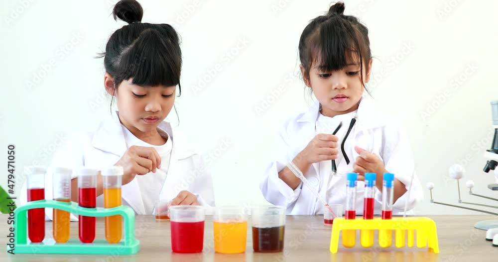 Little girl asian cute little student child learning research and doing a chemical experiment while making analyzing and mixing liquid in test tube at home on the table. Little girl asian cute little student child learning research and doing a chemical experiment while making analyzing and mixing liquid in test tube at home on the table.