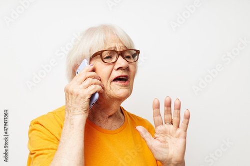 elderly woman in casual t-shirt glasses talking on the phone close-up emotions