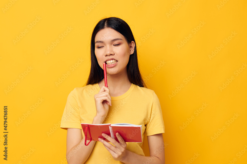 Charming young Asian woman with a notebook and pen in hand isolated background unaltered Charming young Asian woman with a notebook and pen in hand isolated background unaltered