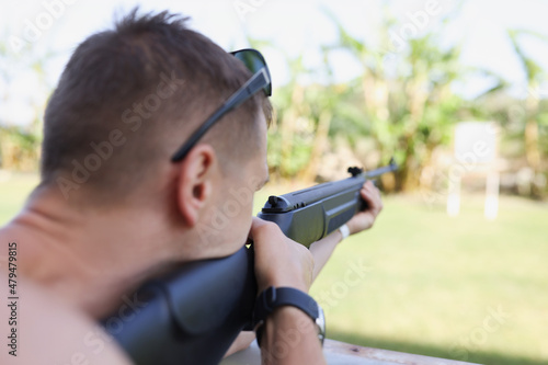 A man is aiming at a target with a gun, close-up