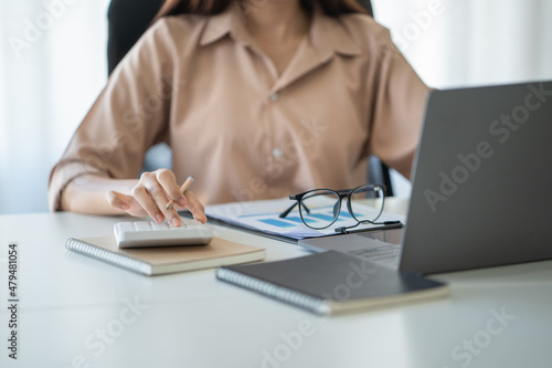 businesswoman hand working with finances about cost and calculator and laptop with tablet on withe desk at the office in the morning light