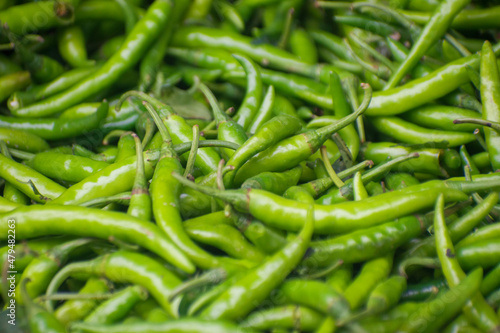 Heap of green Cayenne pepper. Capsicum annuum. It is usually a moderately hot chili pepper used to flavor dishes. © Jahid