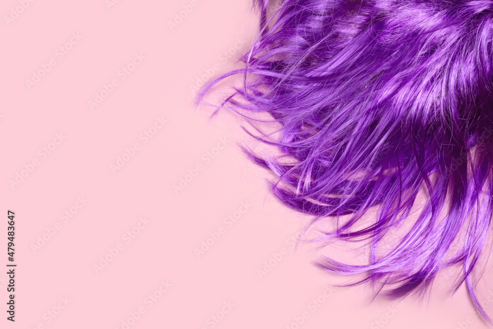 Wig in a trendy Very Peri color lies on a pink table. Creativity, beauty, fashion concept.
