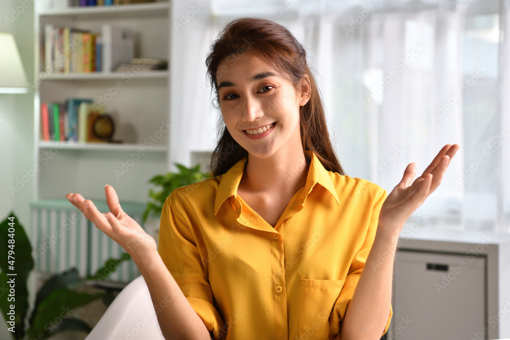 Portrait shot of happy friendly and confident Asian businesswoman making video call, looking at camera and talking, discussing strategy with partners online at home