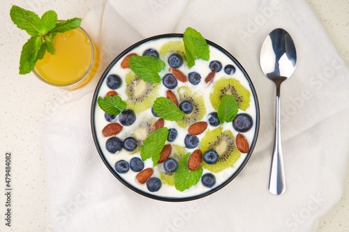 Natural and organic yogurt bowl with blueberries, kiwi slices and almonds on a white background. Top view.