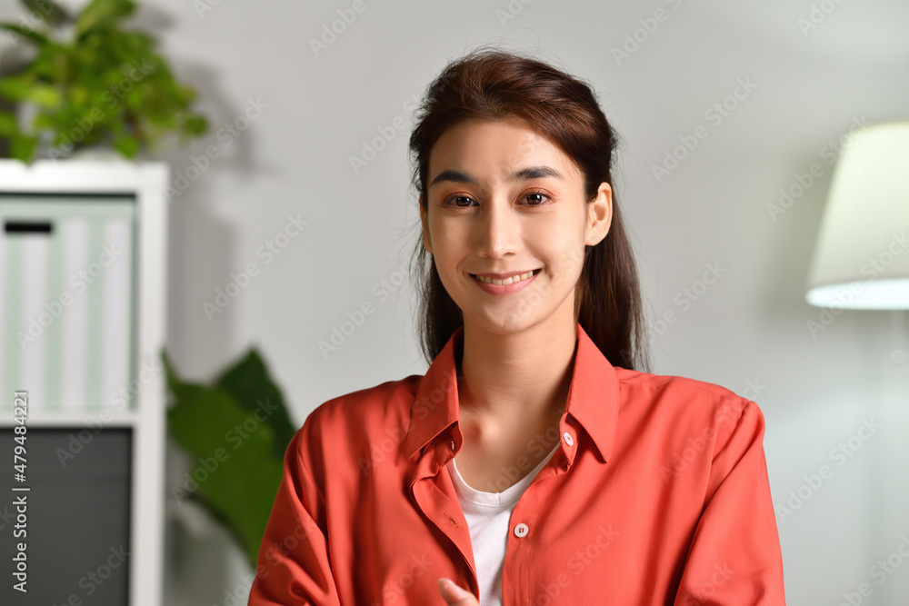 Portrait shot of happy friendly and confident Asian businesswoman making video call, looking at camera and talking, discussing strategy with partners online at home