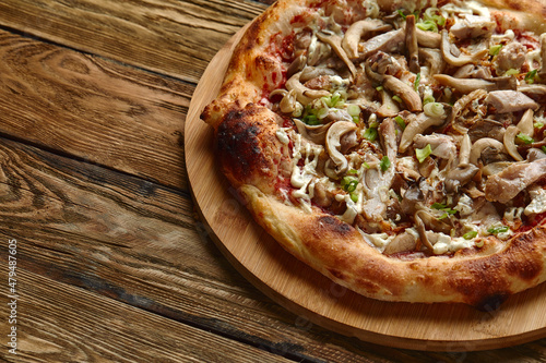 Delicious homemade pizza with mozzarella, mushrooms, beef and chicken. Wooden background, selective focus.