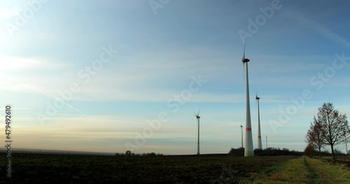 Time-lapse of a early morning as the sun rises on a small wind turbine farm with farmland in the foreground as it gets brighter and clouds moving by. photo