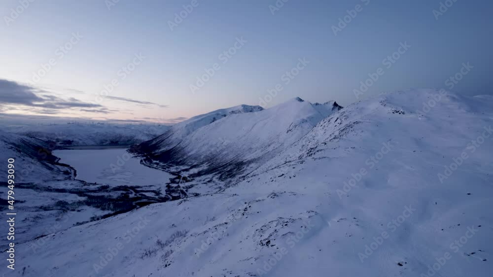 The arctic island of Kvaløya during midwinter. the sun never rises over the horizon. this is sunrise the arctic winter. viewed from a mountain peak perspective The arctic island of Kvaløya during midwinter. the sun never rises over the horizon. this is sunrise the arctic winter. viewed from a mountain peak perspective