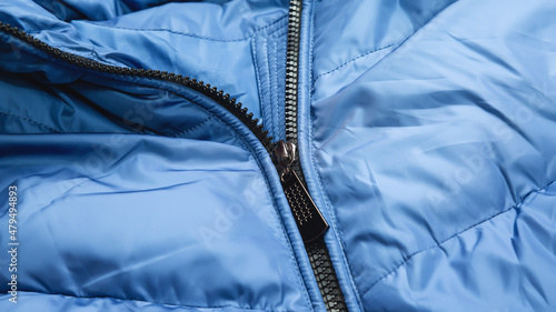 Close-up on blue puffer jacket texture with zipper. Fabric background photo