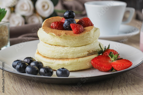 Close-up of Japanese specialties called souffle pancakes with berry on top served on a wooden table
