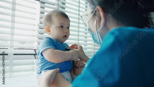 Asian pediatrician examining and listening lungs of little baby with stethoscope. photo