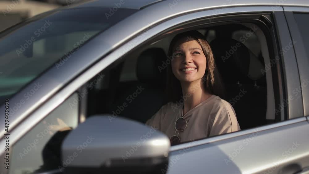 A young woman is sitting in the car in the driver's seat. The man is giving the car key through the window. She is smiling and thanks. She is looking at him. 4K