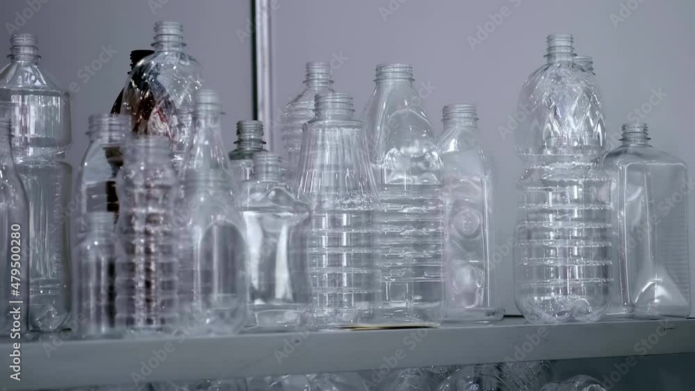 Samples of different plastic bottles. Lots of plastic bottles piled up behind glass. Shot in motion. Closeup Samples of different plastic bottles. Lots of plastic bottles piled up behind glass. Shot in motion. Closeup