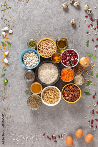 Concept of vegetarian food and diet on gray concrete background, legumes, seeds and cereals in colored bowls grouped with copy space