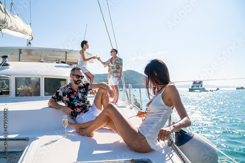 Photography Group of Caucasian people friends enjoy luxury party drinking champagne together while catamaran boat sailing in the ocean
