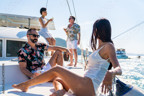 Photography Group of Caucasian people friends enjoy luxury party drinking champagne together while catamaran boat sailing in the ocean