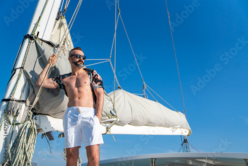 Portrait of Caucasian man enjoy luxury lifestyle catamaran boat sailing with looking at beautiful nature sea at summer sunset. Handsome male relaxing outdoor activity on tropical travel vacation trip