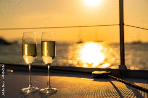 Two Champagne glass on the tray for serving to passenger tourist on luxury catamaran boat sailing in the ocean at summer sunset. Tropical travel vacation sail yacht trip concept © CandyRetriever 