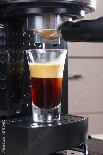 Making short glass of coffee in horn coffee machine.