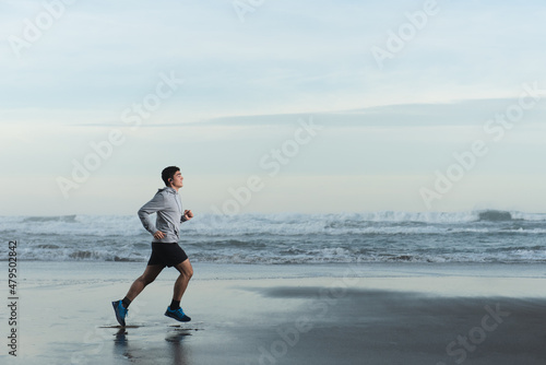 Hispanic teenager runner training at the beach.