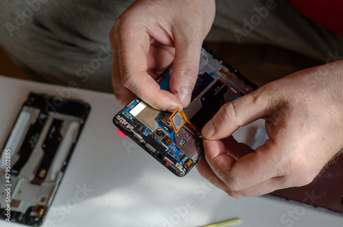 Repair of smartphones concept. A man uninstalls a fingerprint se photo